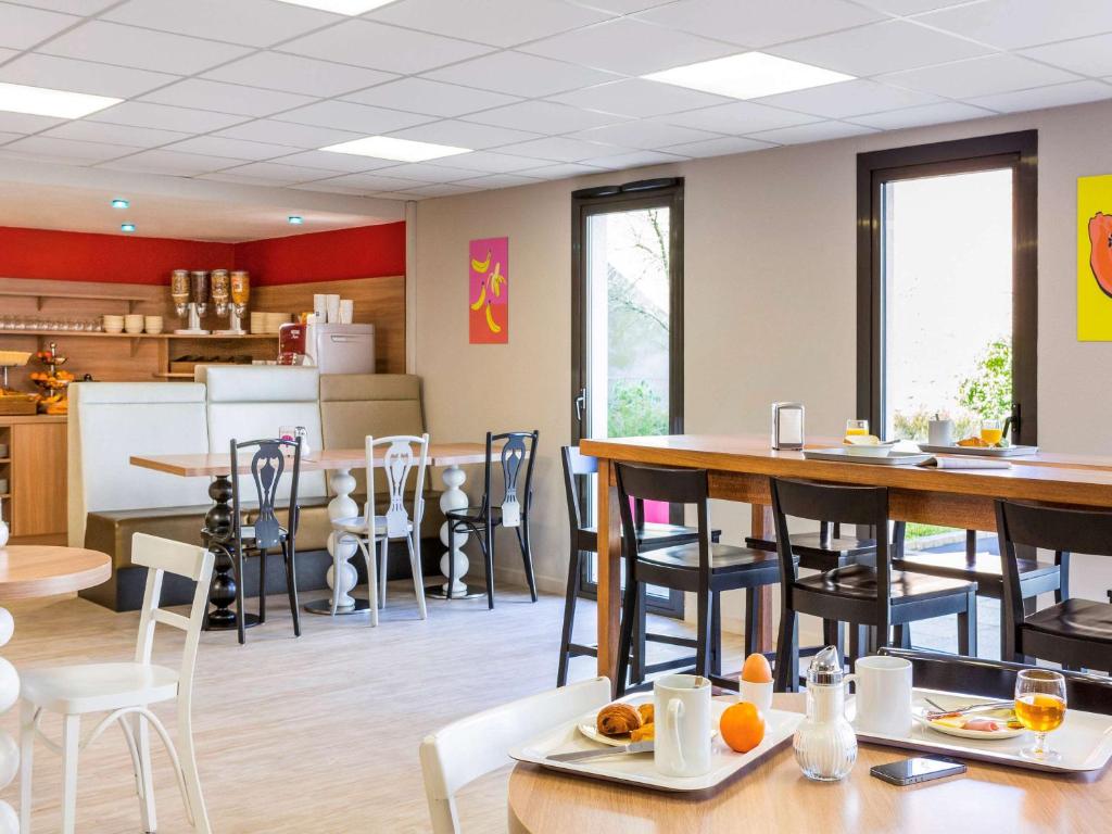 ein Restaurant mit Tischen und Stühlen und eine Küche in der Unterkunft Aparthotel Adagio Access Rennes Centre in Rennes