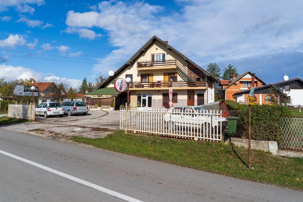 uma casa com uma cerca branca em frente a uma rua em Guest house Padine Zlatibora em Zlatibor