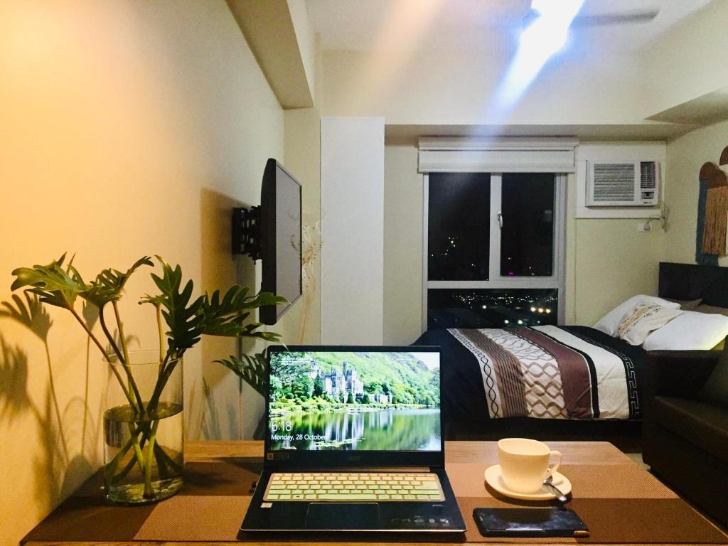Cozy studio in Cebu IT Park في مدينة سيبو: جهاز كمبيوتر محمول على طاولة في غرفة مع سرير
