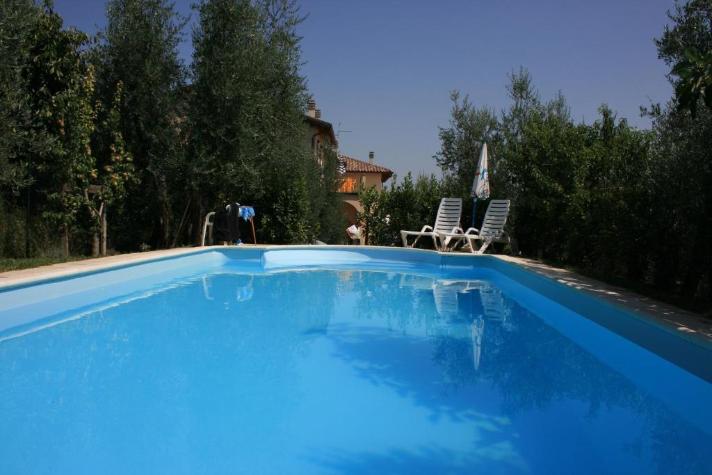 een groot blauw zwembad met 2 ligstoelen bij Casa Fanfulla in Marciano Della Chiana