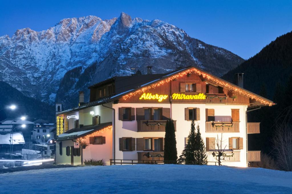 um hotel com uma montanha coberta de neve ao fundo em Albergo Miravalle em Auronzo di Cadore