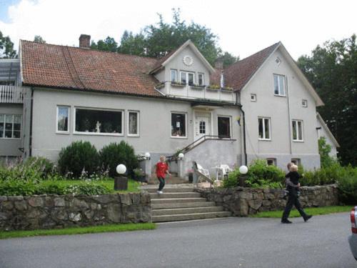 a woman walking down a sidewalk next to a house at Möllegården Bed & Breakfast in Tyringe