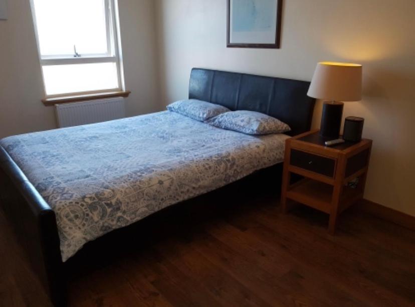 a bedroom with a bed and a night stand with a lamp at Beachview Apartment in Edinburgh