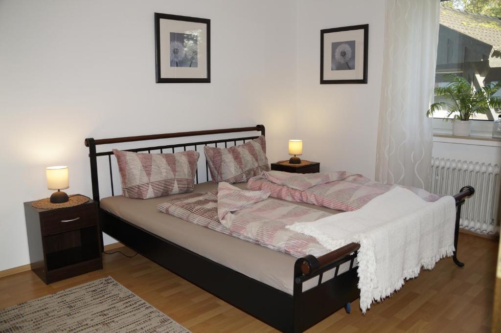een slaapkamer met een bed met 2 nachtkastjes en 2 lampen bij Ferienwohnung auf Resthof in Nordhorn
