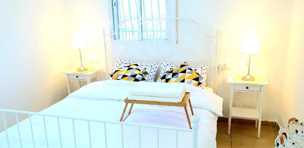 a bedroom with a white bed with a bench on it at Bright Renovated Room Close to Everything in Jerusalem