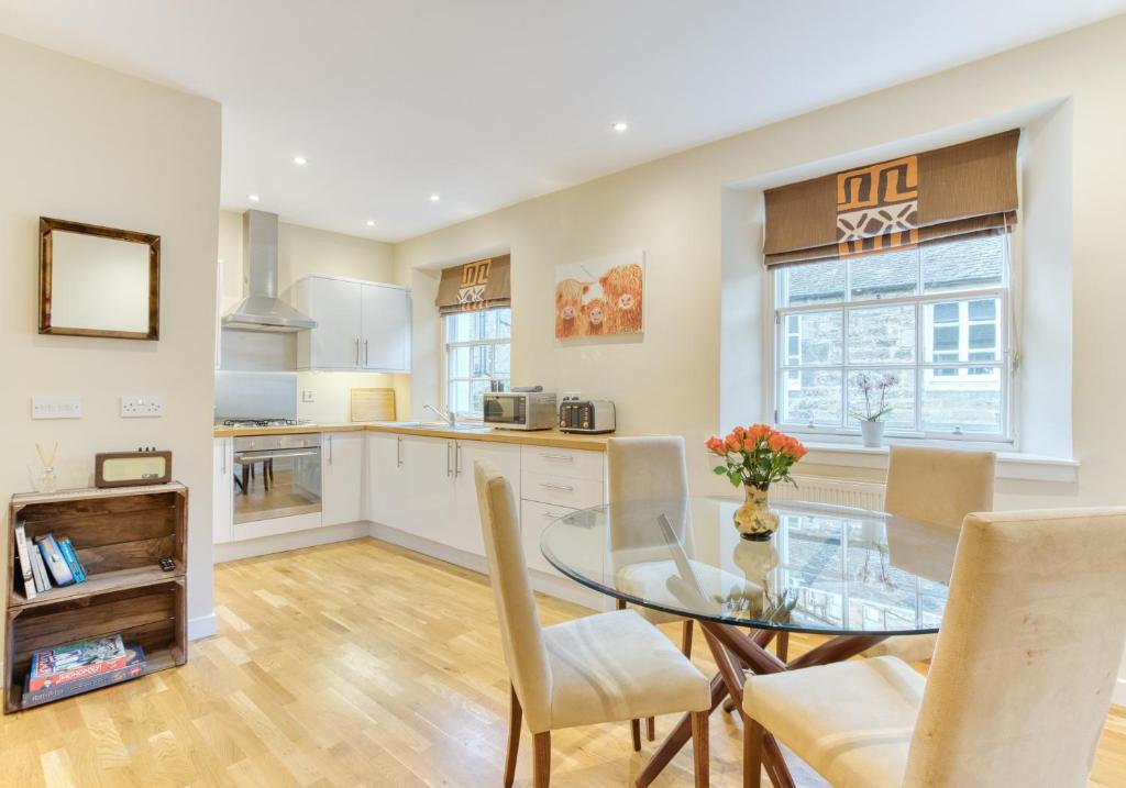 cocina y comedor con mesa de cristal y sillas en The Gloucester Lane Residence, en Edimburgo