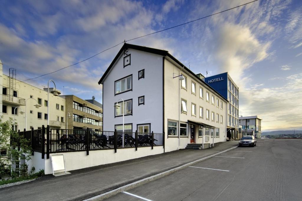 um edifício branco com um telhado preto numa rua em Finnsnes Hotel em Finnsnes