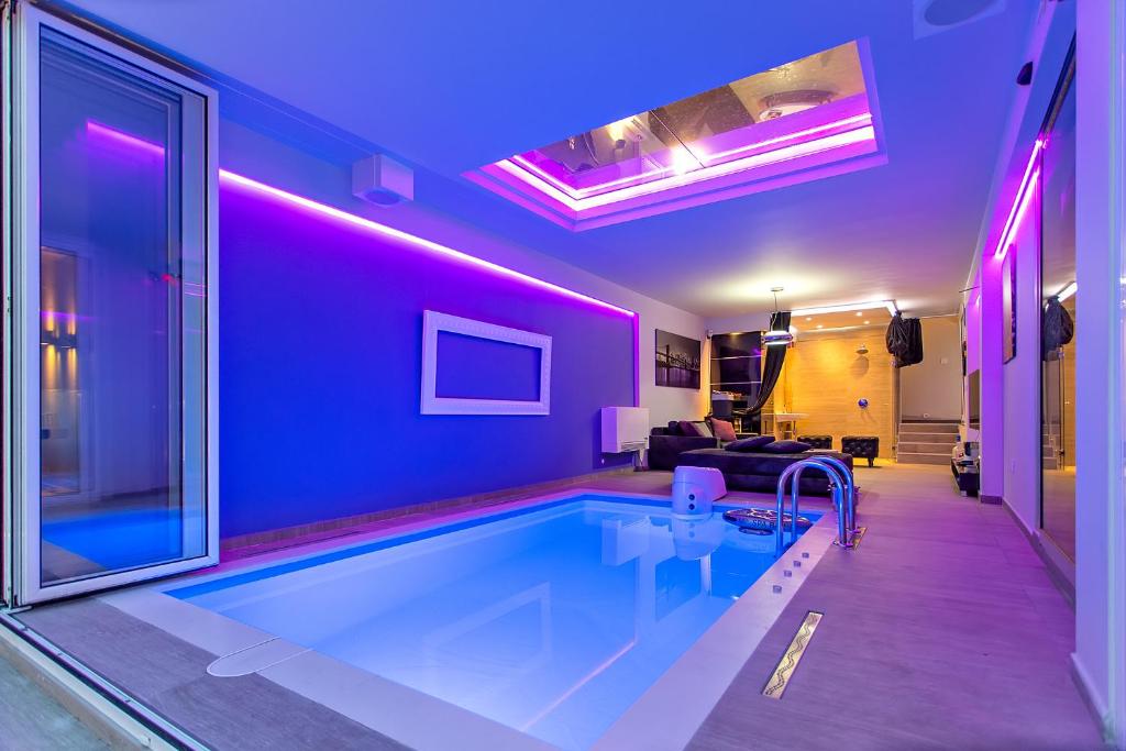 - une piscine dans un salon avec éclairage violet dans l'établissement #1 Luxury Villa with Pool, Gameroom, Spa, Zen Yard, à Belgrade