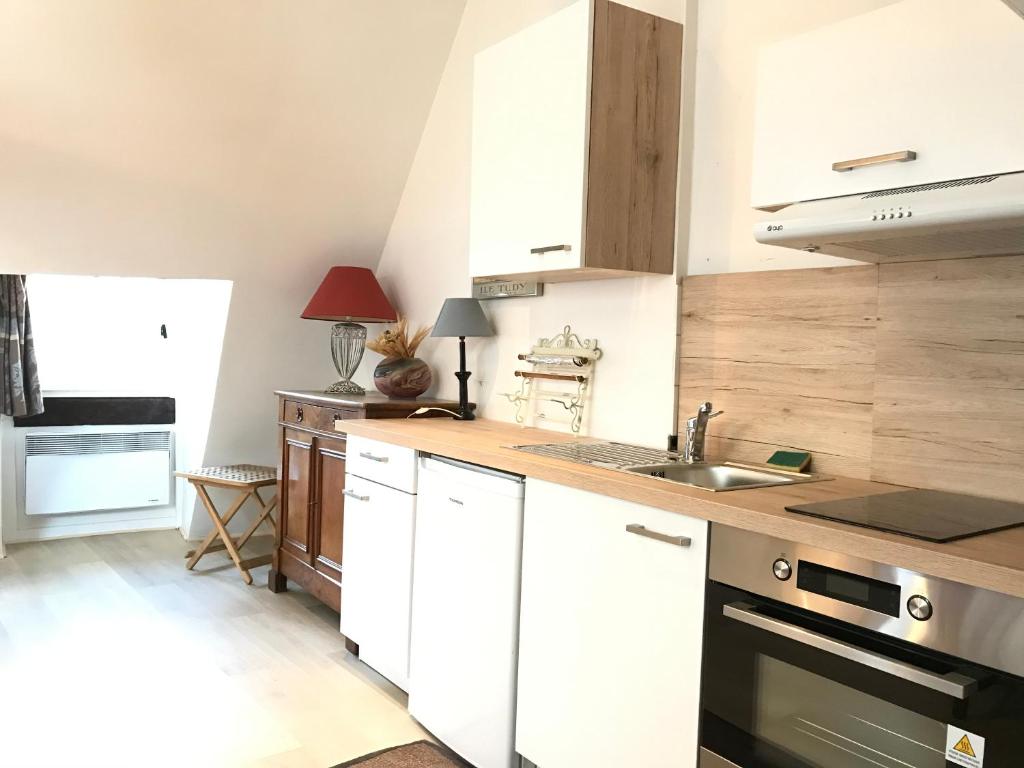 a kitchen with white cabinets and a sink at Le Studio du Gouverneur in Honfleur
