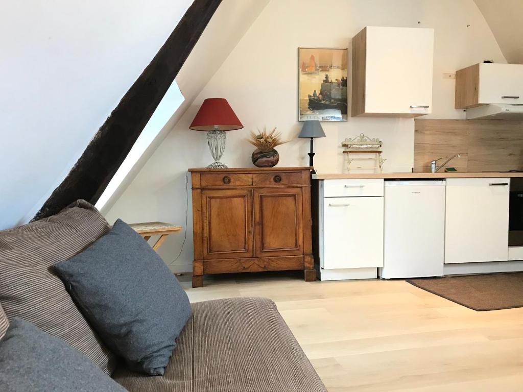 a kitchen with white cabinets and a couch in a room at Le Studio du Gouverneur in Honfleur