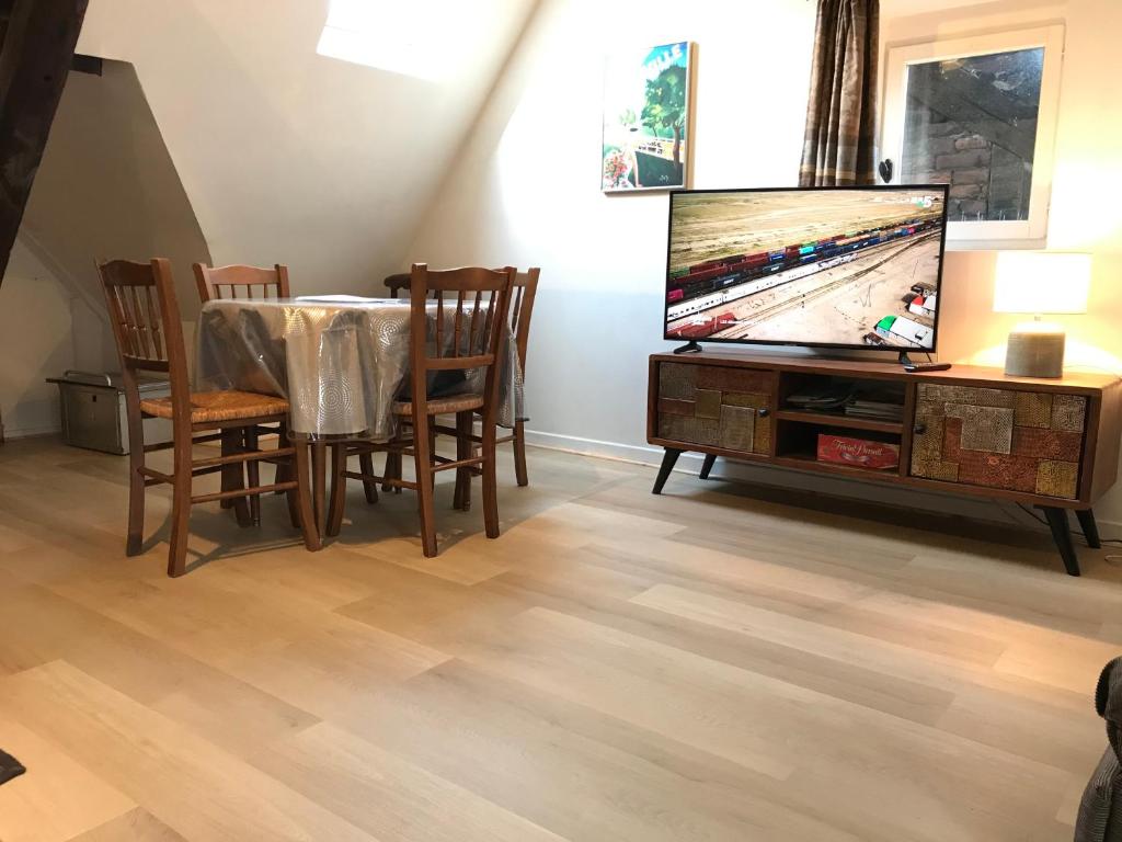 a living room with a dining table and a television at Le Studio du Gouverneur in Honfleur