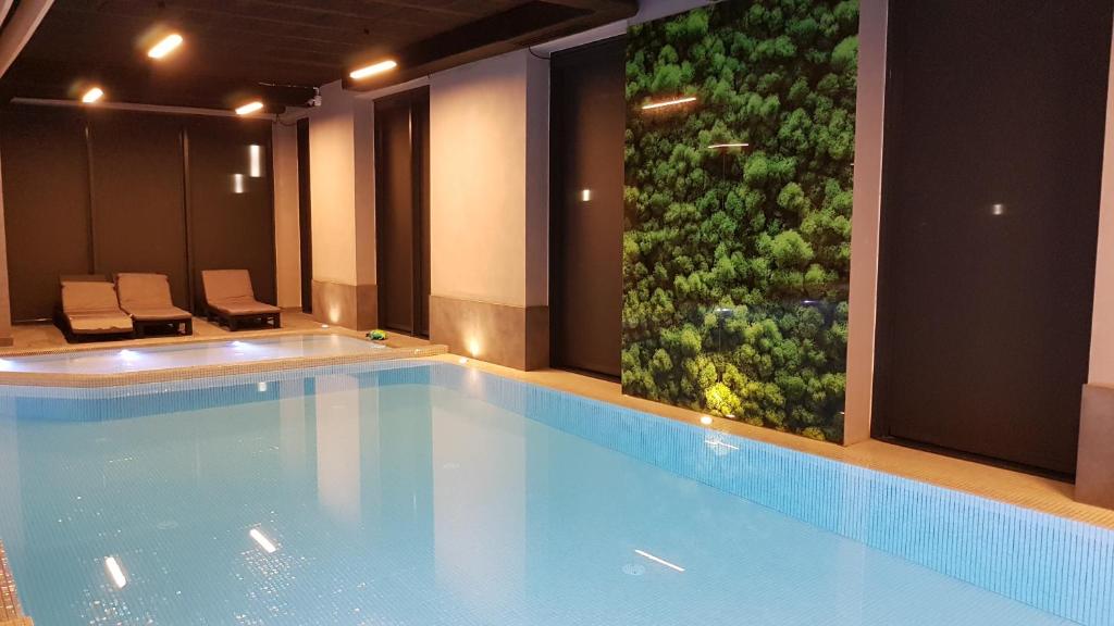 a large swimming pool with a green wall at Apartamenty Przystanek Plaża Sarbinowo in Sarbinowo