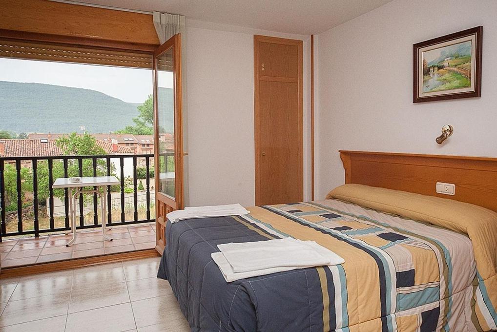 a bedroom with a bed and a balcony at Hostal Vinuesa in Vinuesa