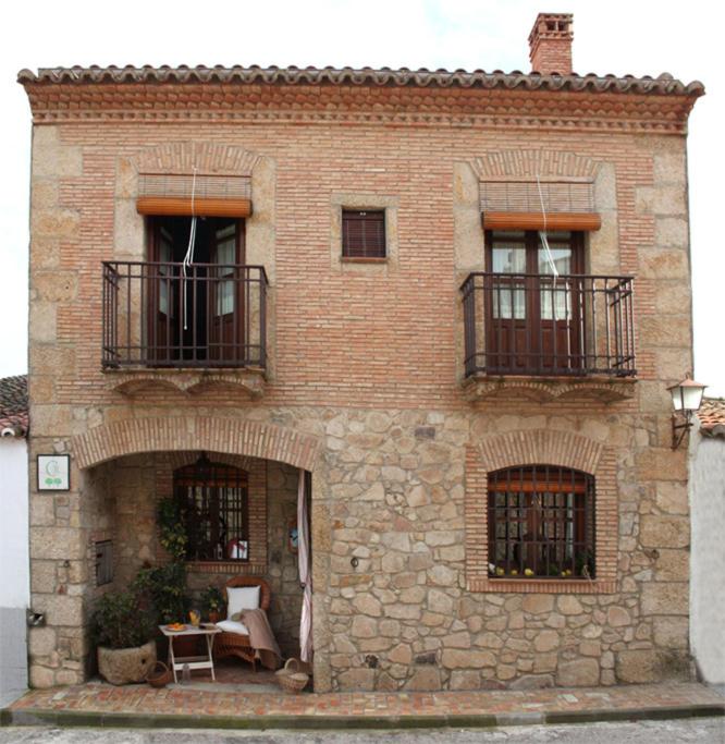 a brick building with two balconies and a table at Casa Rural El Tenado in Aldea de Trujillo