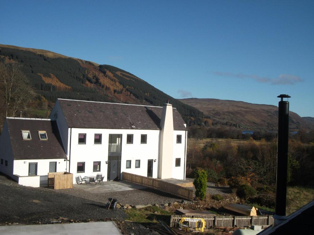 a white building with a hill in the background at Craggan House in Lochearnhead