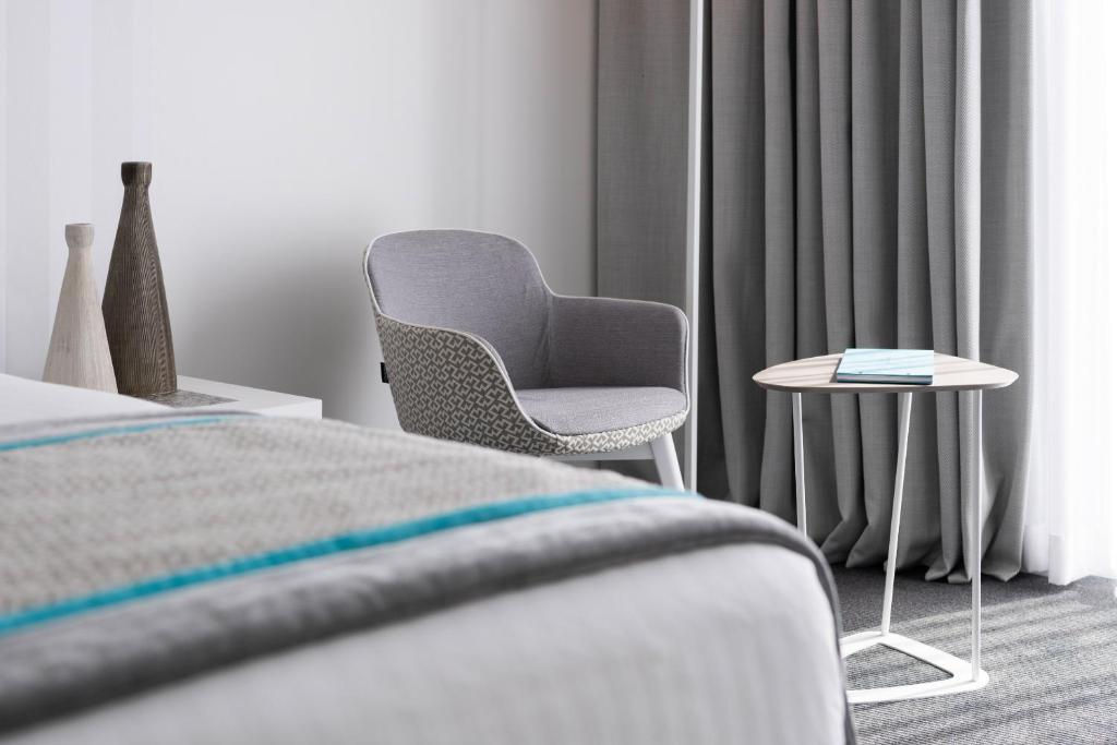 a bedroom with a chair and a side table at Hotel Juliani - Boutique Hotel in St. Julianʼs