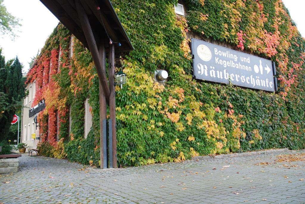 ein Schild an der Seite eines Gebäudes mit Pflanzen in der Unterkunft Räuberschänke in Oederan