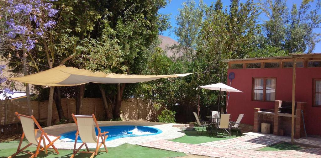 un patio con sillas, una sombrilla y una piscina en Cabaña en Valle de Elqui, en Horcón