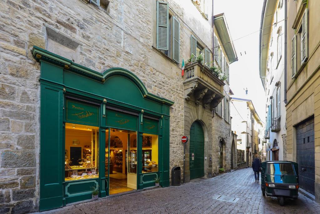 a building with a green storefront on a street at Altana Bergamo Home in Bergamo