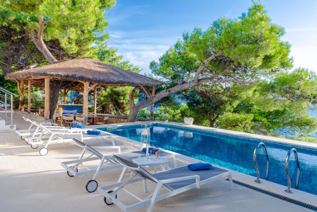 a swimming pool with chairs and a gazebo at Villa Anni in Primošten