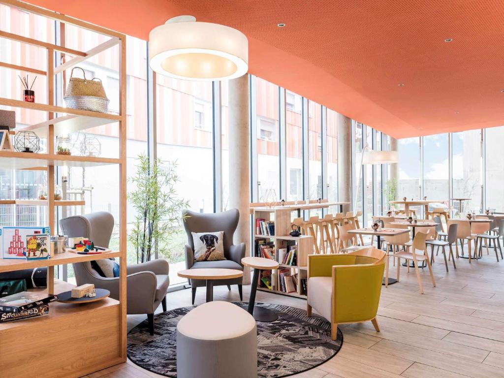 een restaurant met tafels, stoelen en ramen bij Aparthotel Adagio Access Paris Massy Gare in Massy