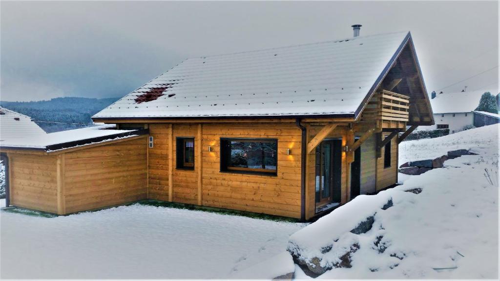 a small wooden cabin with snow on the roof at Châlet de la Feigne in Anould