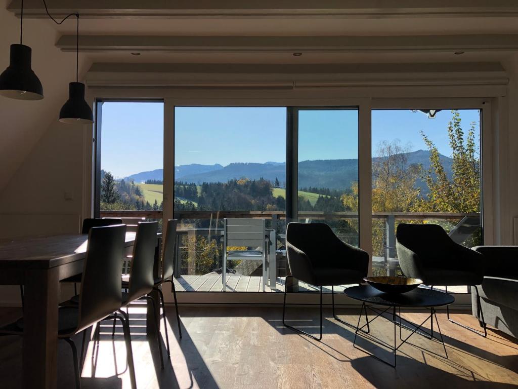 una sala da pranzo con tavolo, sedie e una grande finestra di Haus mit Bergblick a Siegsdorf