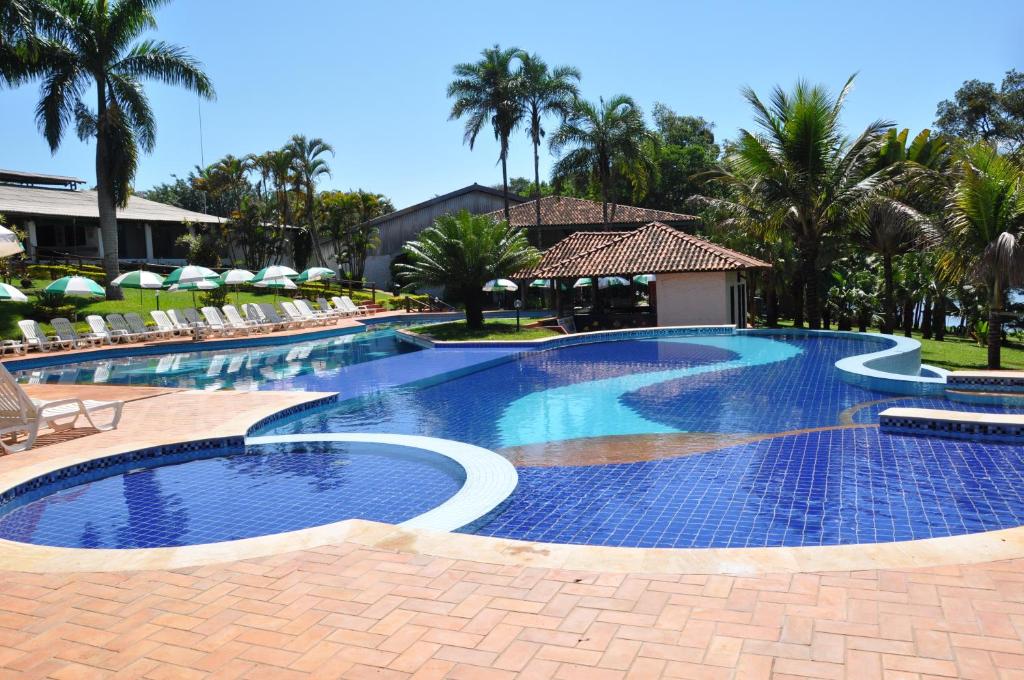 une grande piscine avec des chaises et des palmiers dans l'établissement Hotel Berro D´Agua, à Avaré