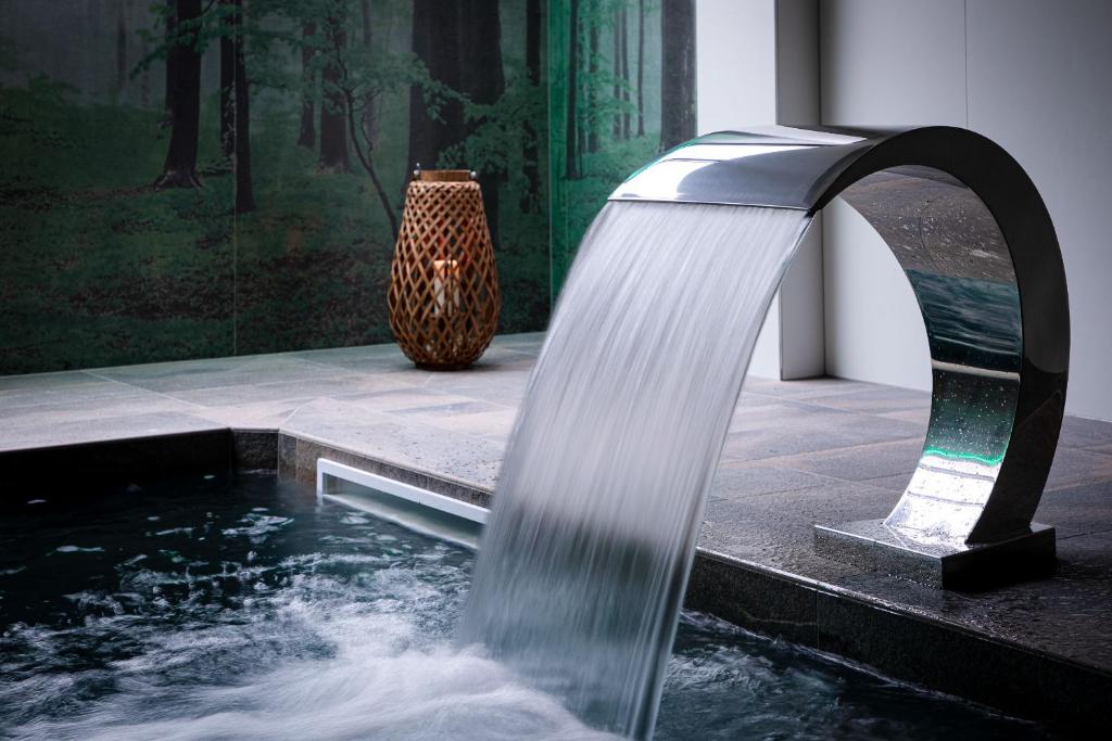 Europe Haguenau – Hotel & Spa في آغينو: نافورة مياه في غرفة بها مزهرية