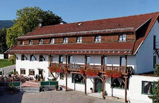 un grand bâtiment avec un toit rouge et une terrasse dans l'établissement Hotel Winterl, à Bernried am Starnberger See