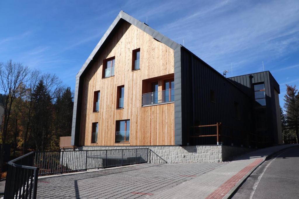 a large wooden building with a gambrel roof at Apartman Milíř - ADULTS ONLY in Bedřichov