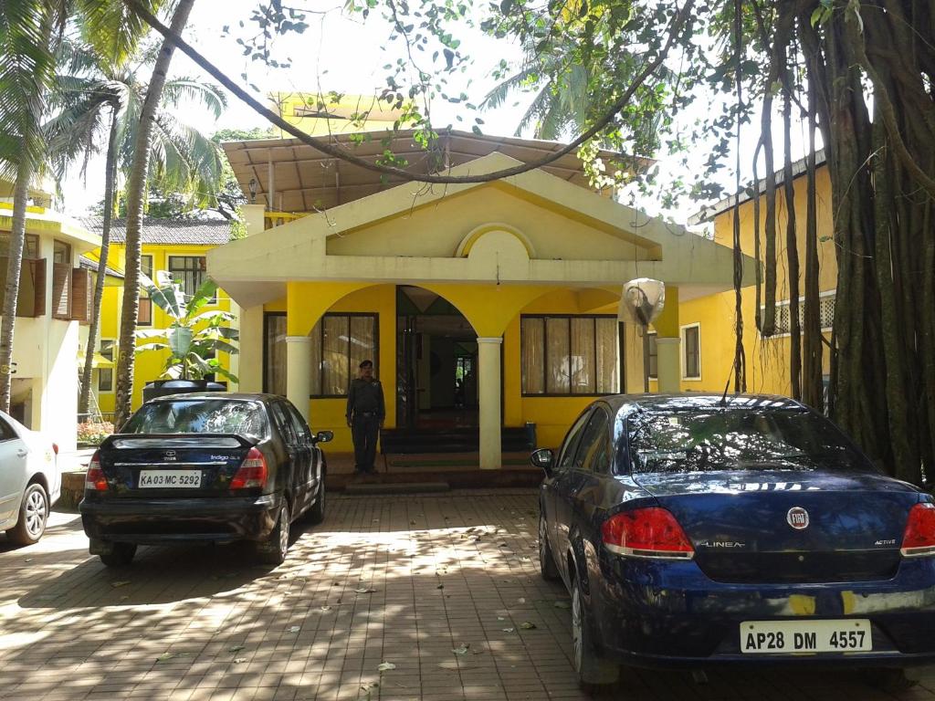 zwei Autos, die vor einem gelben Gebäude geparkt sind in der Unterkunft Old Goa Residency in Velha Goa