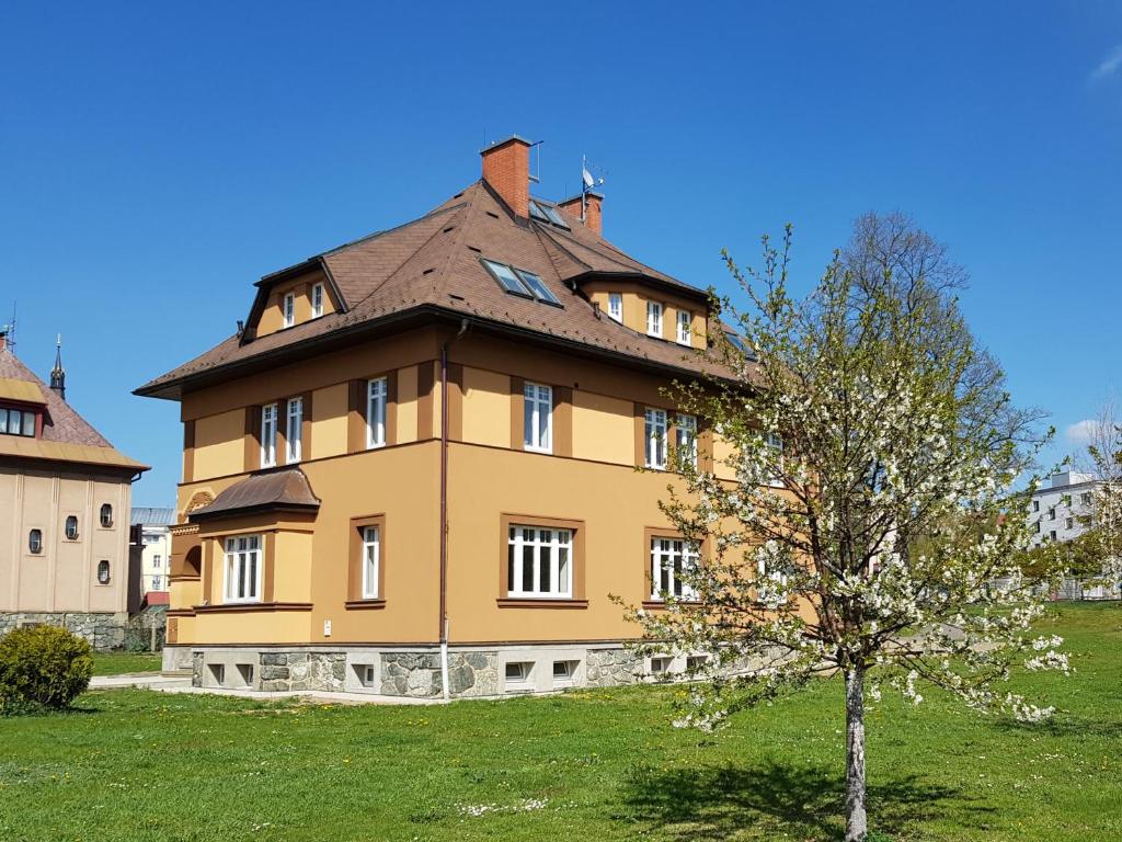 una grande casa gialla con un albero di fronte di Kavárna a penzion REICHL a Králíky