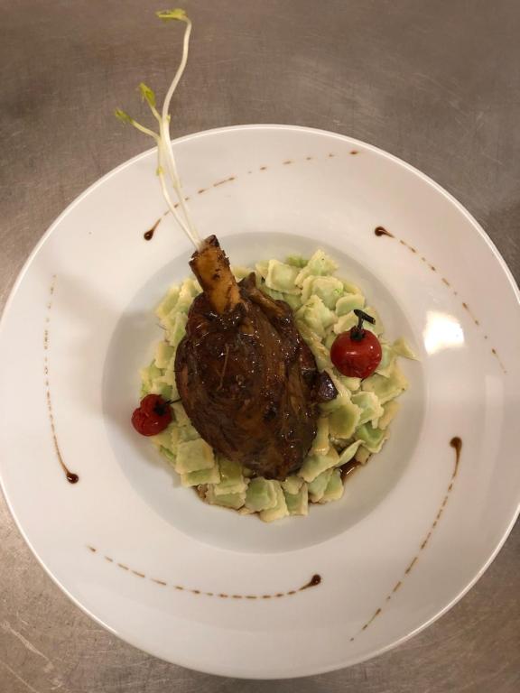 a plate of food with a piece of meat on pasta at Logis Hôtel l&#39;Abricotine in Tain-lʼHermitage