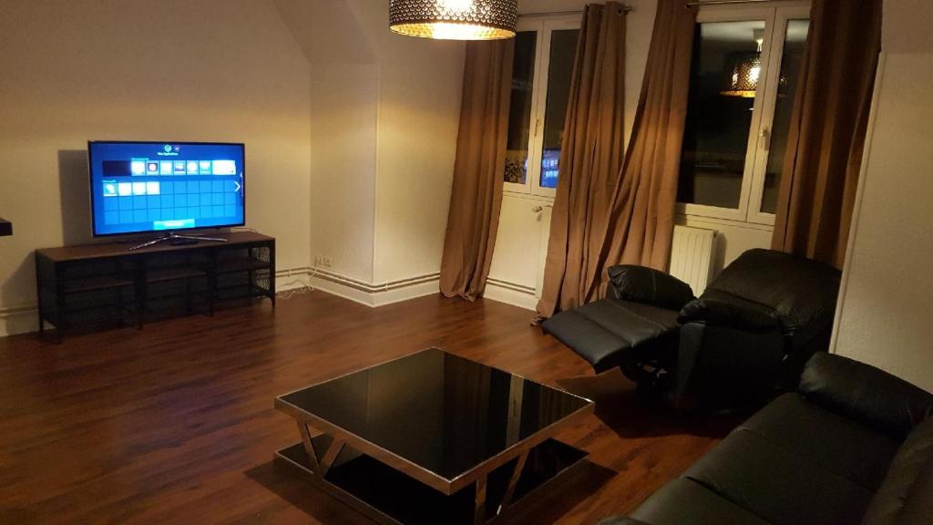 uma sala de estar com um sofá e uma televisão em Bel appartement en plein coeur de ville em Le Creusot