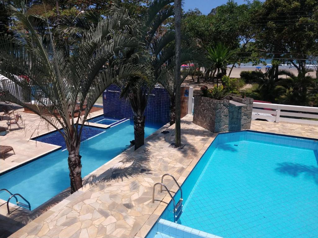 una piscina en un complejo con palmeras en Pousada Vistazul - Piscina Climatizada - Pé na Areia, en Bertioga