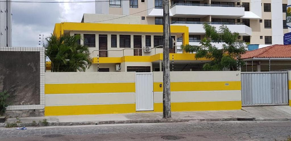 una cerca amarilla y blanca frente a un edificio en Casa Aeroclube en João Pessoa