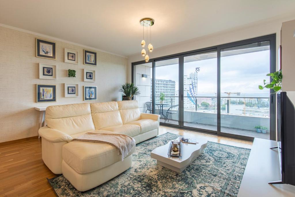 uma sala de estar com um sofá branco e uma grande janela em River View Apartment by Lisbon Heart em Lisboa