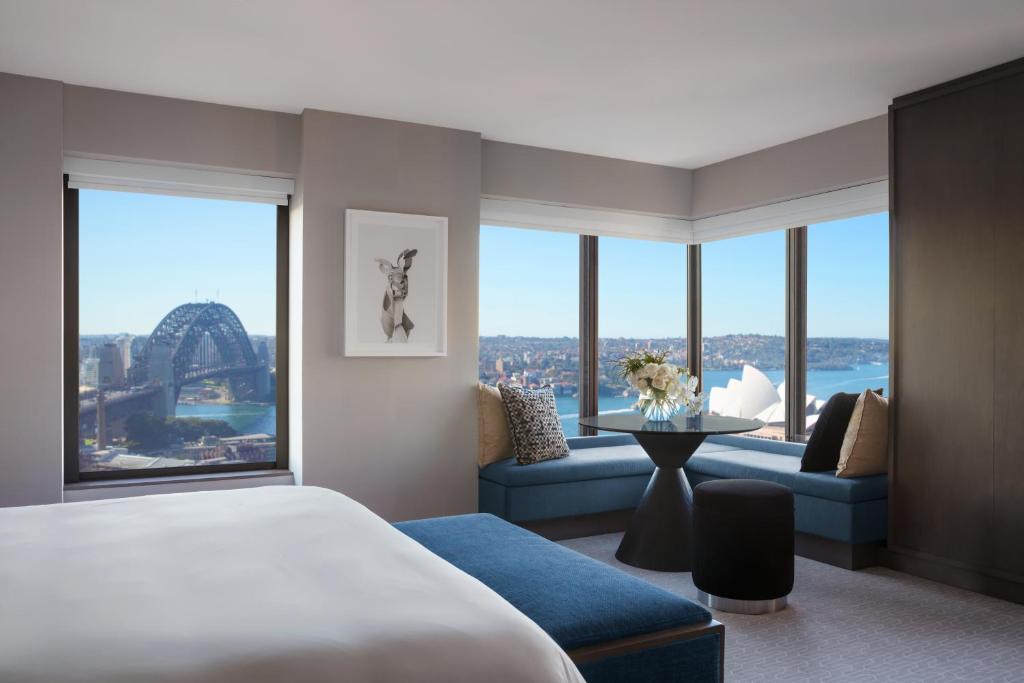 a hotel room with a bed and a couch and windows at Four Seasons Hotel Sydney in Sydney