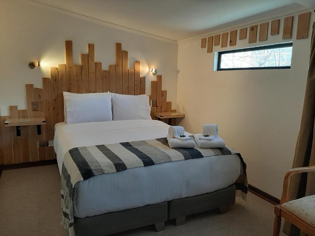 a bedroom with a large bed with two stuffed animals on it at Hotel Tehuelche Natura in Coihaique