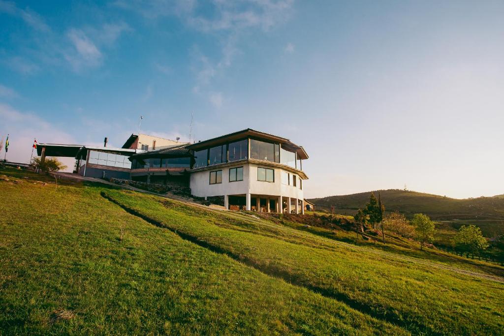 a large white house sitting on top of a lush green hillside at Hotel Fazenda Rota dos Cânions in Bom Jardim da Serra