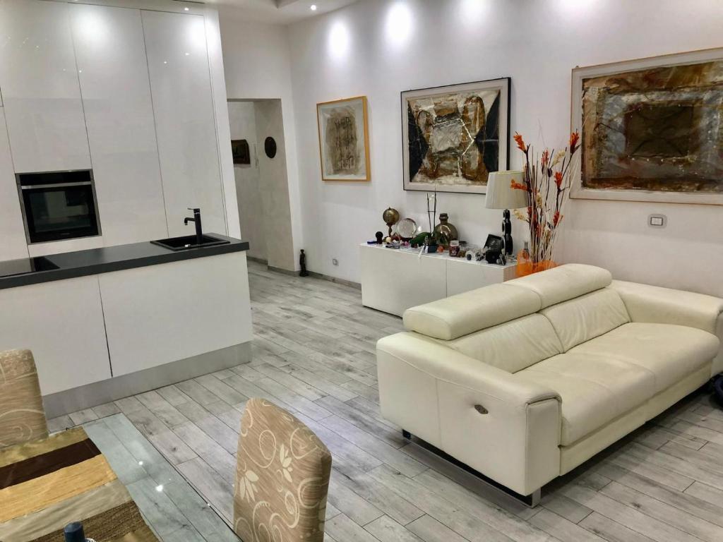 ein Wohnzimmer mit einem weißen Sofa und einer Küche in der Unterkunft Allegra's House Vaticano in Rom