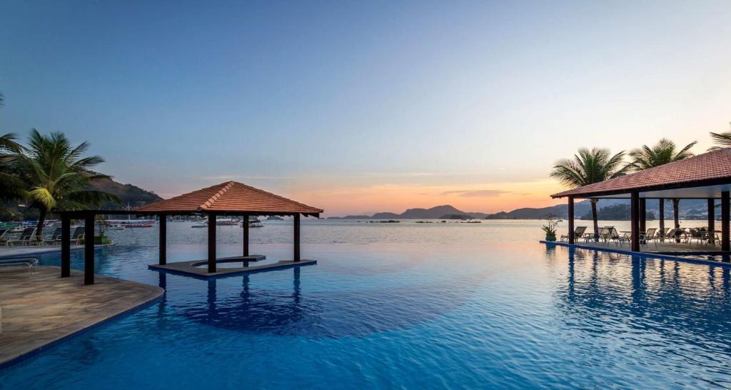 uma piscina de resort com vista para o oceano em Porto Bali - Resort Mercure em Angra dos Reis