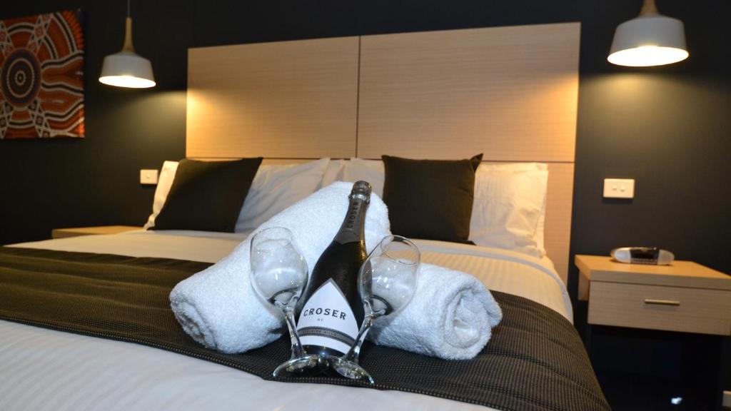 um quarto de hotel com uma cama com sapatos e toalhas em The Astor Suites em Goulburn
