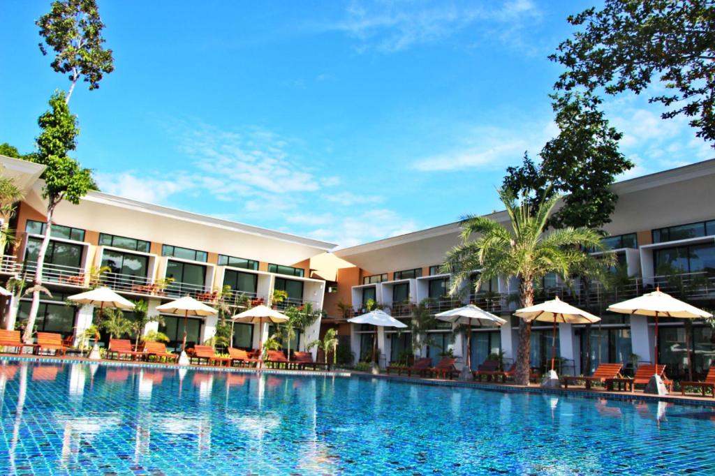 a hotel with a large swimming pool with tables and umbrellas at Bundhaya Resort in Ko Lipe