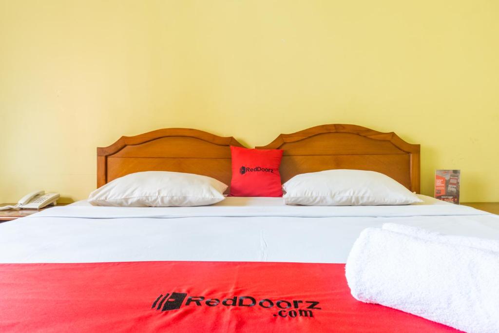 1 cama con 2 almohadas y manta roja en RedDoorz Plus near Brawijaya Museum, en Malang