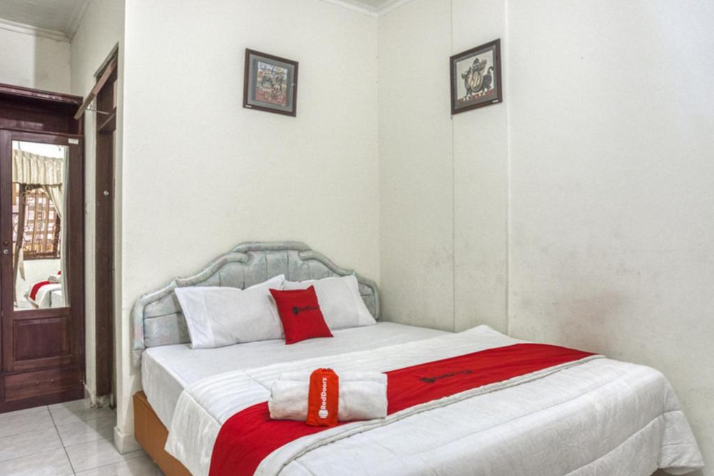 een slaapkamer met een bed met een rode deken bij RedDoorz Syariah @ Raya Tajem Maguwo in Kalasan