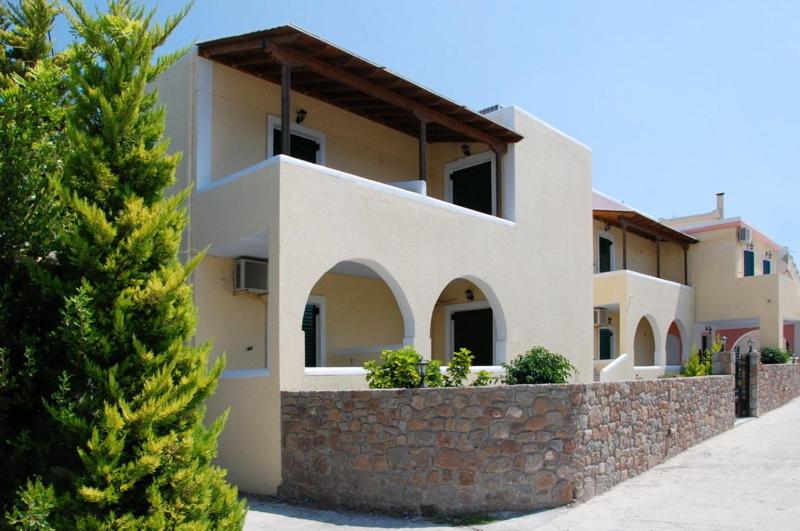 a house with a stone wall next to a tree at Alvi Studios in Perdhika