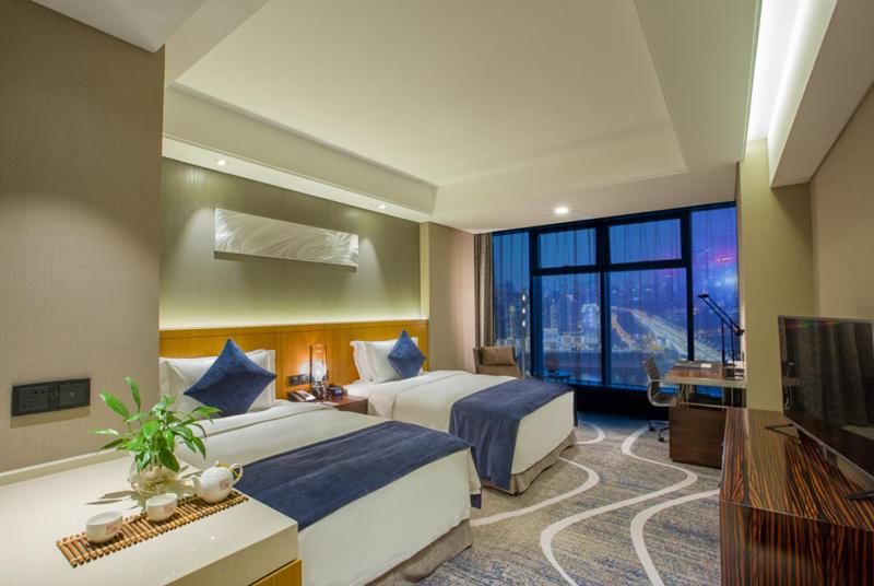 a hotel room with two beds and a television at C Plaza Hotel in Chongqing