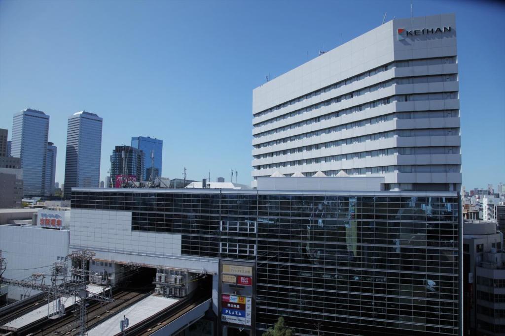 a large building in a city with a train at Hotel Keihan Kyobashi Grande in Osaka
